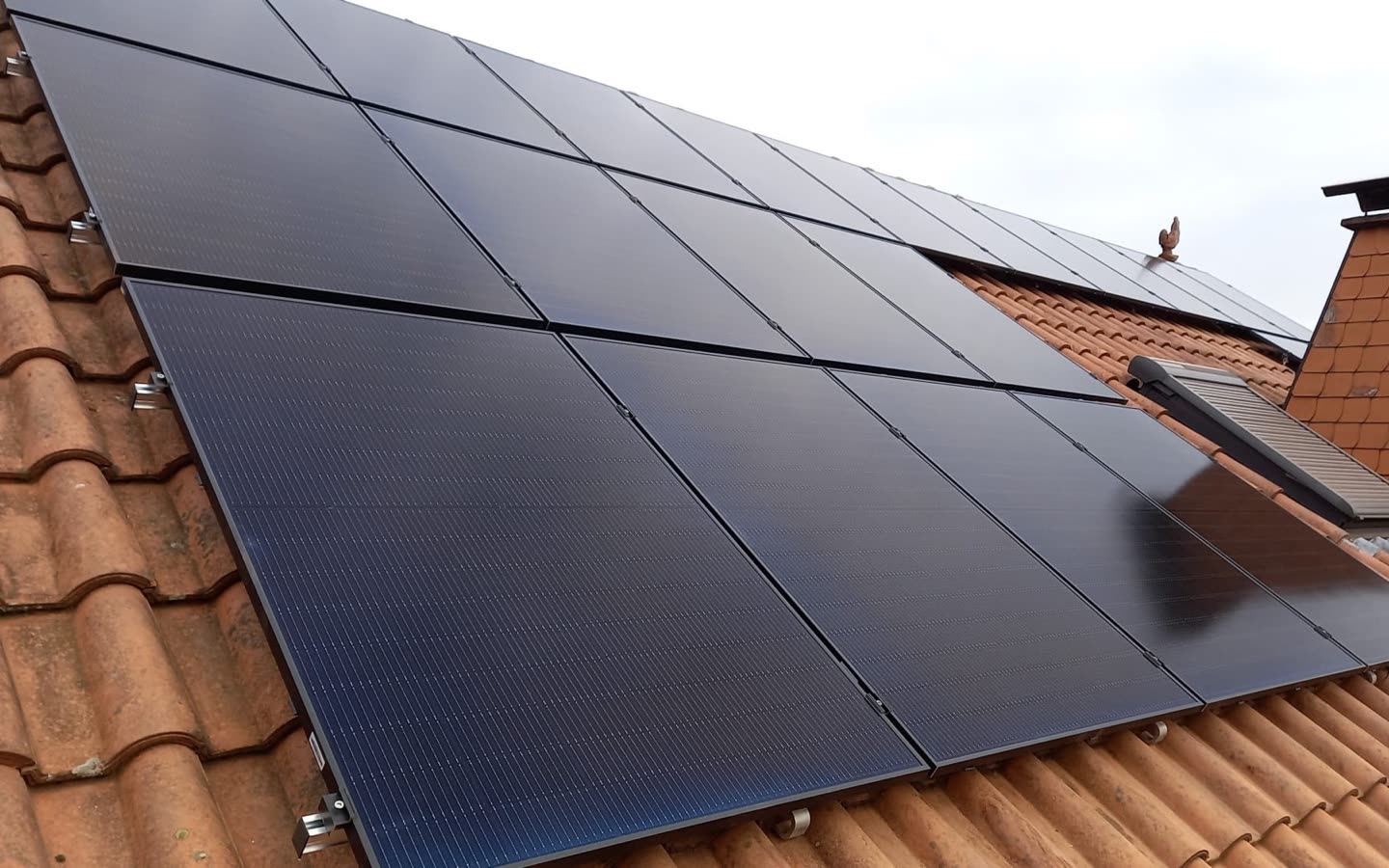 Fertig montierte Photovoltaikanlage auf einem Satteldach, gleichmäßig ausgerichtete schwarze Module