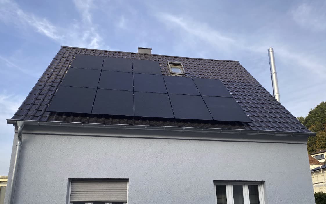 Einfamilienhaus mit schwarzen Photovoltaikmodulen auf dunklem Ziegeldach